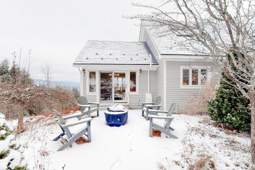 a white house with two benches in the snow at Campton White Mountains Retreat in Campton