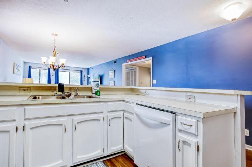 una cucina con armadi bianchi e parete blu di Dogwood 201 a Myrtle Beach