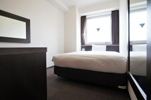 a hotel room with a bed and a window at Green Rich Hotel Suizenji in Kumamoto