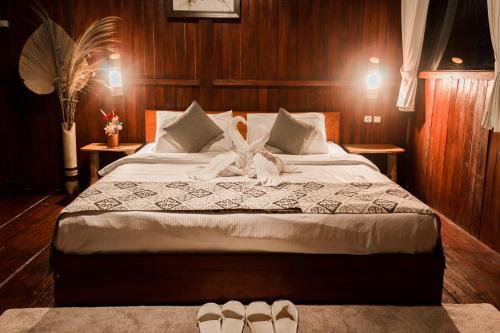 a bedroom with a large bed with slippers on it at Da'Kayu Bali Homestay in Munduk