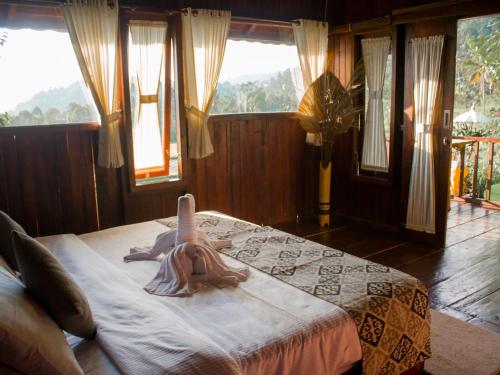 Da'Kayu Bali Homestay في موندوك: غرفة نوم مع دمية على سرير مع نوافذ
