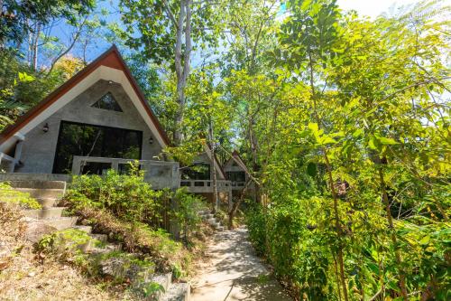 a house in the woods with a path leading to it at Baan Rai Me Rak Organic Farmstay in Ban Pa Khlok