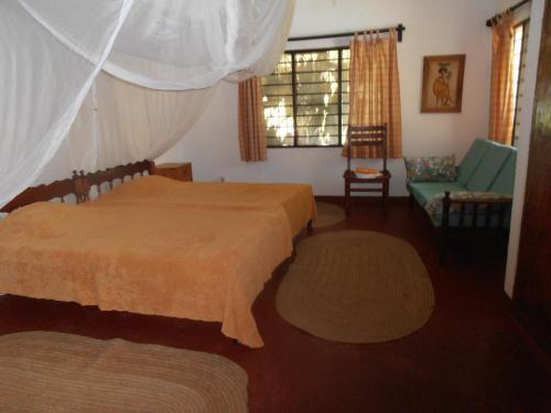 a bedroom with two beds and a couch and a window at Sunset Villa Eco Friendly House in Kilifi