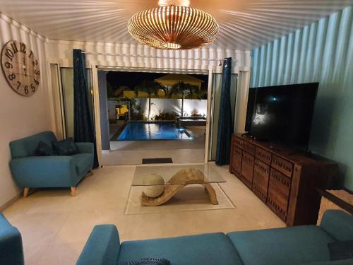 a living room with a blue couch and a tv at LA VILLA ROSAYA - Piscine & Jacuzzi in Saint-Pierre