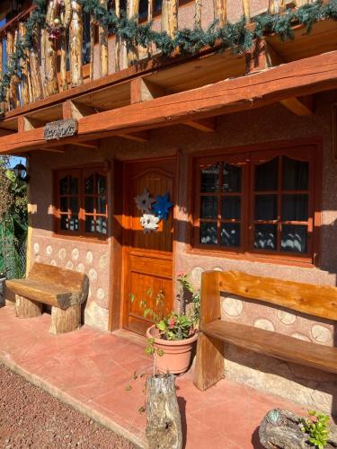 ein Gebäude mit zwei Holzbänken und einer Veranda in der Unterkunft Cabañas Quinta San Agustin in Zacatlán