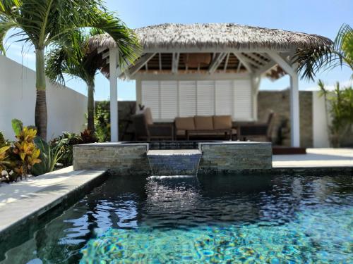 a swimming pool in front of a house with a gazebo at LA VILLA ROSAYA - Piscine & Jacuzzi in Saint-Pierre