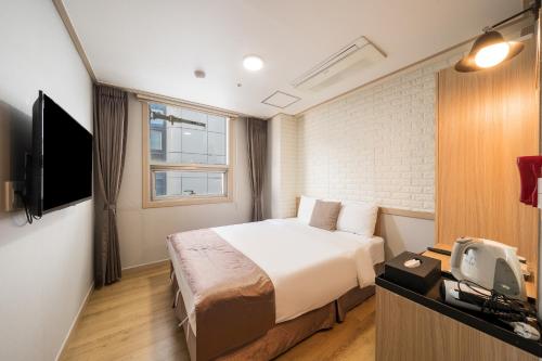 um quarto de hotel com uma cama e uma televisão em The Stay Hotel Myeongdong em Seul