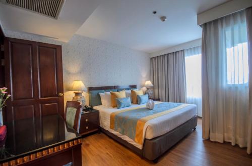 a hotel room with a bed and a dresser at Prince Palace Hotel - SHA Extra Plus in Bangkok