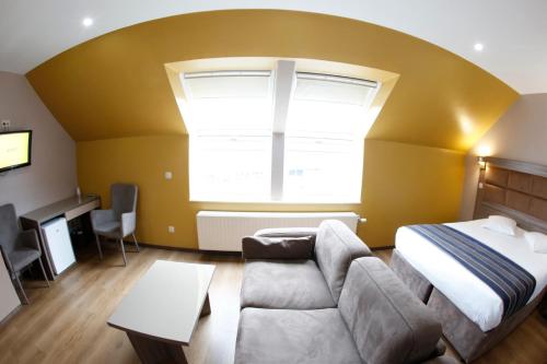 a bedroom with a bed and a couch and a window at Hotel Midi-Zuid in Brussels