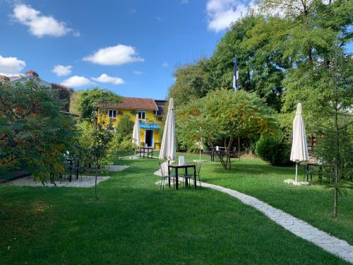 a garden with tables and umbrellas on the grass at Pensiunea Deceneu in Slănic