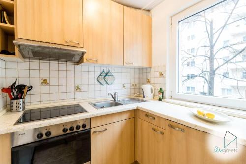 cocina con armarios de madera, fregadero y ventana en Modern apartment in central spot en Berlín
