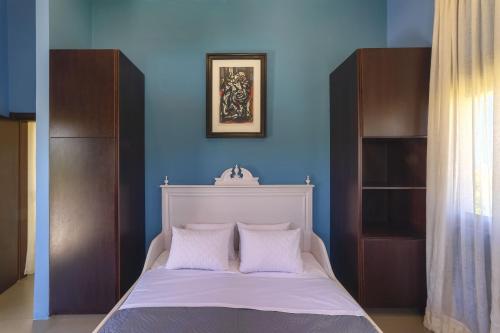 a bedroom with a white bed with a blue wall at Villa Sfedami in Mikro Metochi