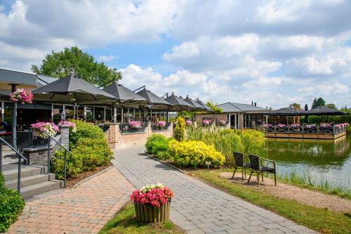 ein Gebäude mit Tischen und Stühlen neben einem Wasserkörper in der Unterkunft Maashof in Venlo