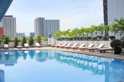 una piscina con sedie a sdraio e un edificio di Golden Tulip Sovereign Hotel Bangkok a Bangkok