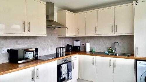 a kitchen with white cabinets and a black microwave at Property Hunter 23 in Darlington