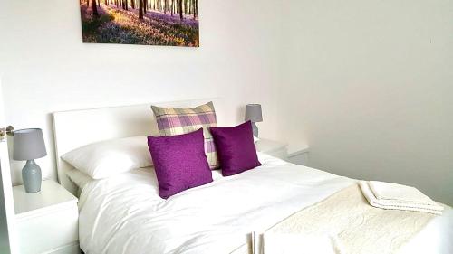 uma cama branca com duas almofadas roxas em Property Hunter 23 em Darlington