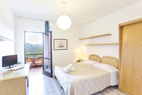 a bedroom with a bed and a television and a balcony at Resort Le Picchiaie in Portoferraio