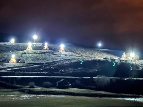a snowy field at night with lights on at UVAC-Etno selo Kaćo in Sjenica