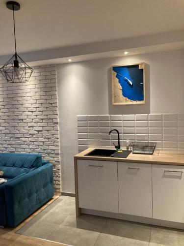 グディニャにあるBlue Apartment in vibrant heart of Gdyniaのリビングルーム(青いソファ付)、キッチン