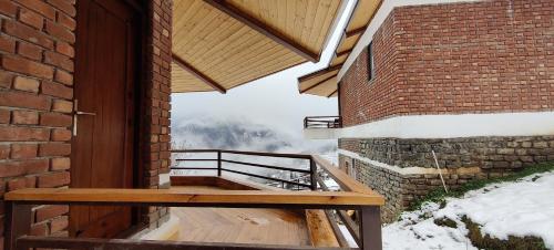 a wooden porch with a view of a snow covered mountain at Casa Himalaya, Auli in Joshīmath