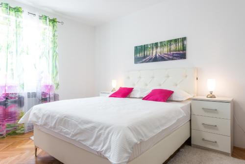 a bedroom with a large white bed with pink pillows at Villa Markoc in Cavtat