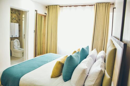 a bedroom with a bed with blue and yellow pillows at The Warwick Hotel, Nanyuki in Nanyuki