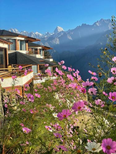 a field of pink flowers with mountains in the background at Casa Himalaya, Auli in Joshīmath