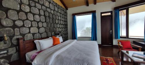 a bedroom with a bed and a stone wall at Casa Himalaya, Auli in Joshīmath