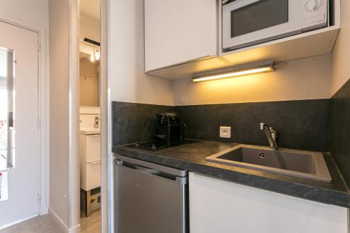 une cuisine avec un évier et un micro-ondes dans l'établissement love secret port nature 7, au Cap d'Agde