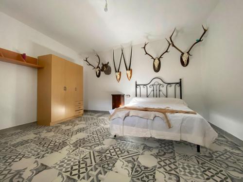 1 dormitorio con 1 cama y cuernos en la pared en Casa rural La Hidalga, en Sierro
