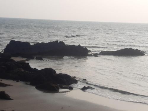 a beach with some rocks in the water at Om Ganesh Guest House Cliffside in Arambol