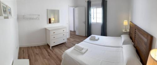 - une chambre blanche avec 2 lits et une commode dans l'établissement Moderno apartamento en San Bartolomé, à Séville