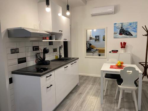 Studio Apartman Lora في Lipik: مطبخ مع دواليب بيضاء وطاولة بيضاء وغرفة طعام