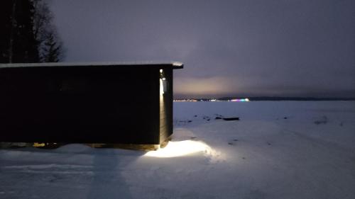 une boîte assise dans la neige la nuit dans l'établissement Loma Luonnonlapsi Loimu-mökki, à Sotkamo