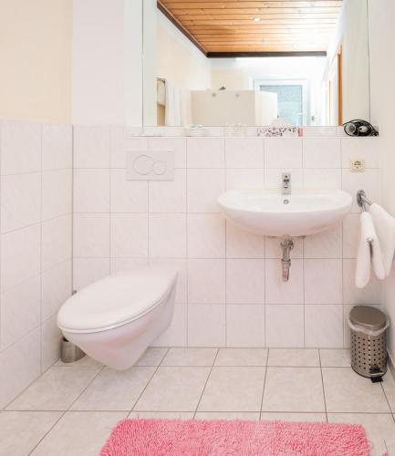 a white bathroom with a toilet and a sink at Gästehaus Kochelsee in Kochel
