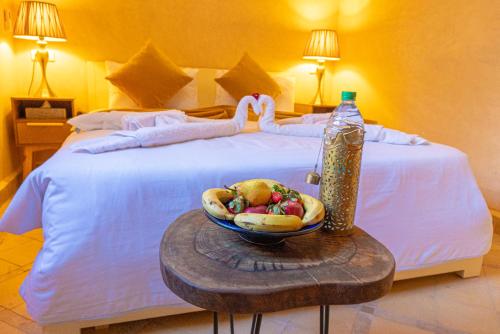 Una cama con un bol de fruta y una botella de agua. en Riad Louaya en Marrakech