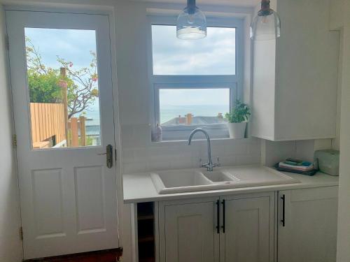 eine weiße Küche mit einem Waschbecken und einem Fenster in der Unterkunft 28 North, Stunning Costal home with Generous Ferry Reduction in Ventnor