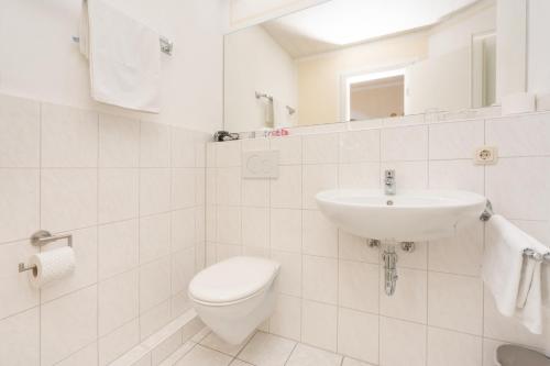 a white bathroom with a toilet and a sink at Gästehaus Kochelsee in Kochel