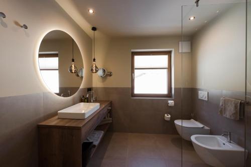 a bathroom with a sink and a toilet and a mirror at Hotel Viertler in Avelengo