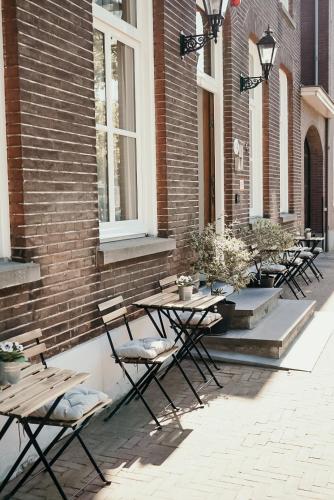 a row of tables and chairs next to a brick building at The Yard hotel Zuidkade in Veghel
