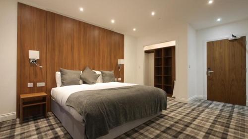 a bedroom with a large bed and a wooden wall at Mango the Hotel in Haggs