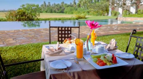 a table with a plate of food and a vase of flowers at Kithala Resort - Thema Collection in Tissamaharama