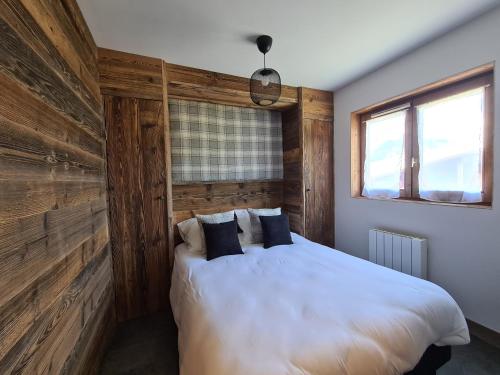 a bedroom with a white bed with a wooden wall at Ecrin des Glaciers Combloux in Combloux