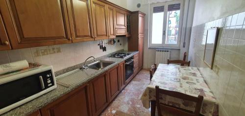 una cocina con armarios de madera, mesa y fregadero en Appartamento Solilo 3 km da Sestri Levante, en Casarza Ligure