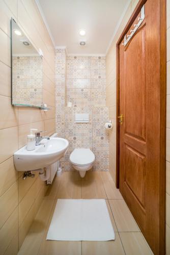 a bathroom with a sink and a toilet and a door at Villa Szilva Vendégház in Szilvásvárad