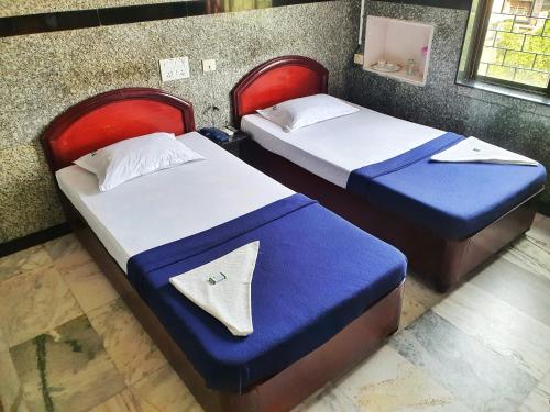 duas camas com lençóis azuis e brancos num quarto em HOTEL GREENS - Puratchi Thalaivar Dr M G Ramachandran Central Railway Station Chennai em Chennai