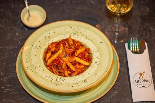 a bowl of pasta on a table with a glass of wine at Modern Mountain in Kolašin