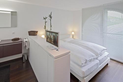 ツェルマットにあるCasa Collinetta 2の白いベッドルーム(ベッド1台、カウンター内のテレビ付)