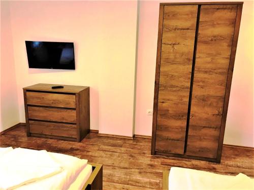 a bedroom with a bed and a dresser with a television at Villa Szilva Vendégház in Szilvásvárad