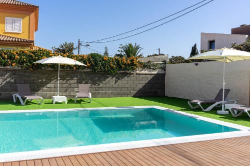 a swimming pool with two chairs and two umbrellas at Albor Suites in Santa Brígida